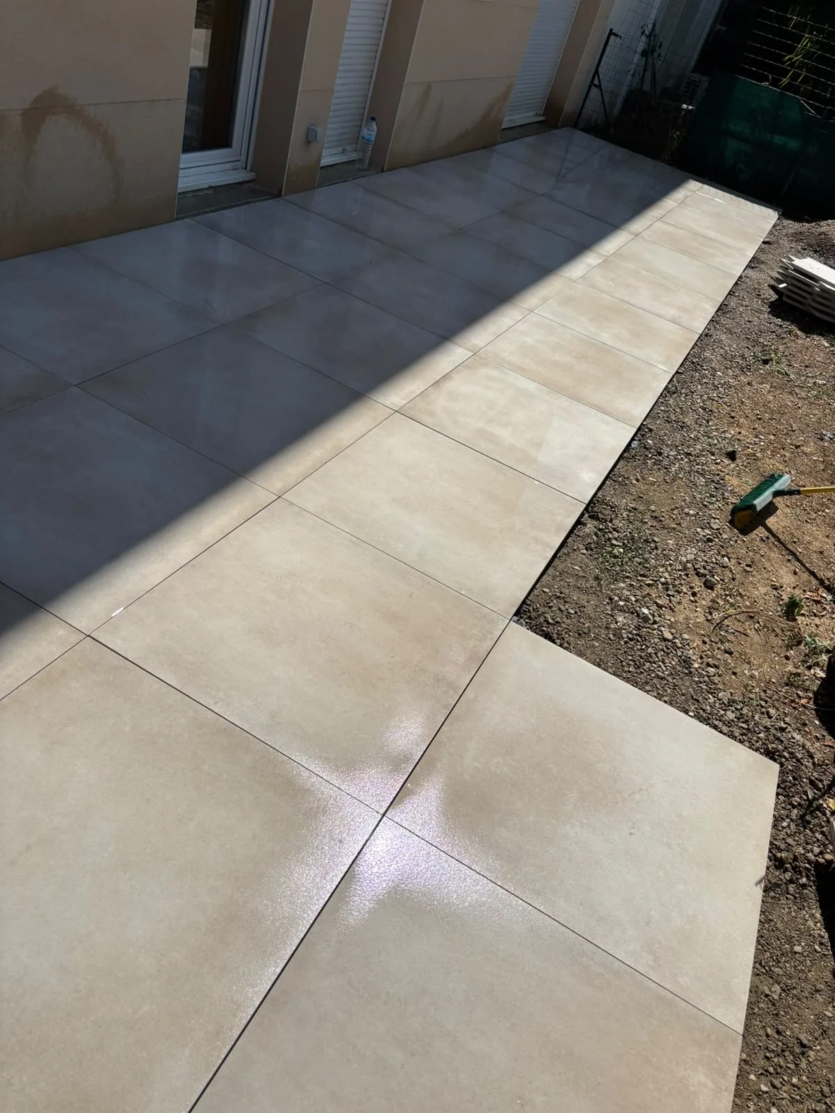 Après — la terrasse terminée, grandes dalles de grès cérame posées sur plots le long de la façade